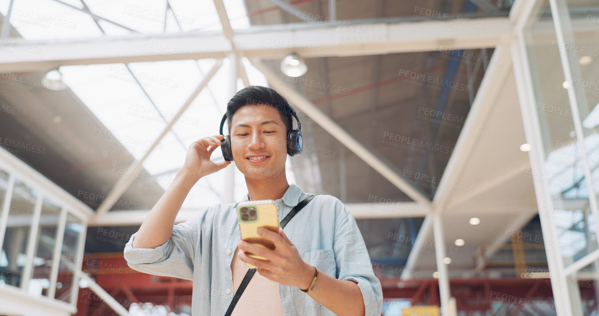 Buy stock photo Walking, phone or happy man in office with headphones on social media, internet or network in a building. Podcast, travel or Asian intern on mobile app to chat or scroll for radio music playlist