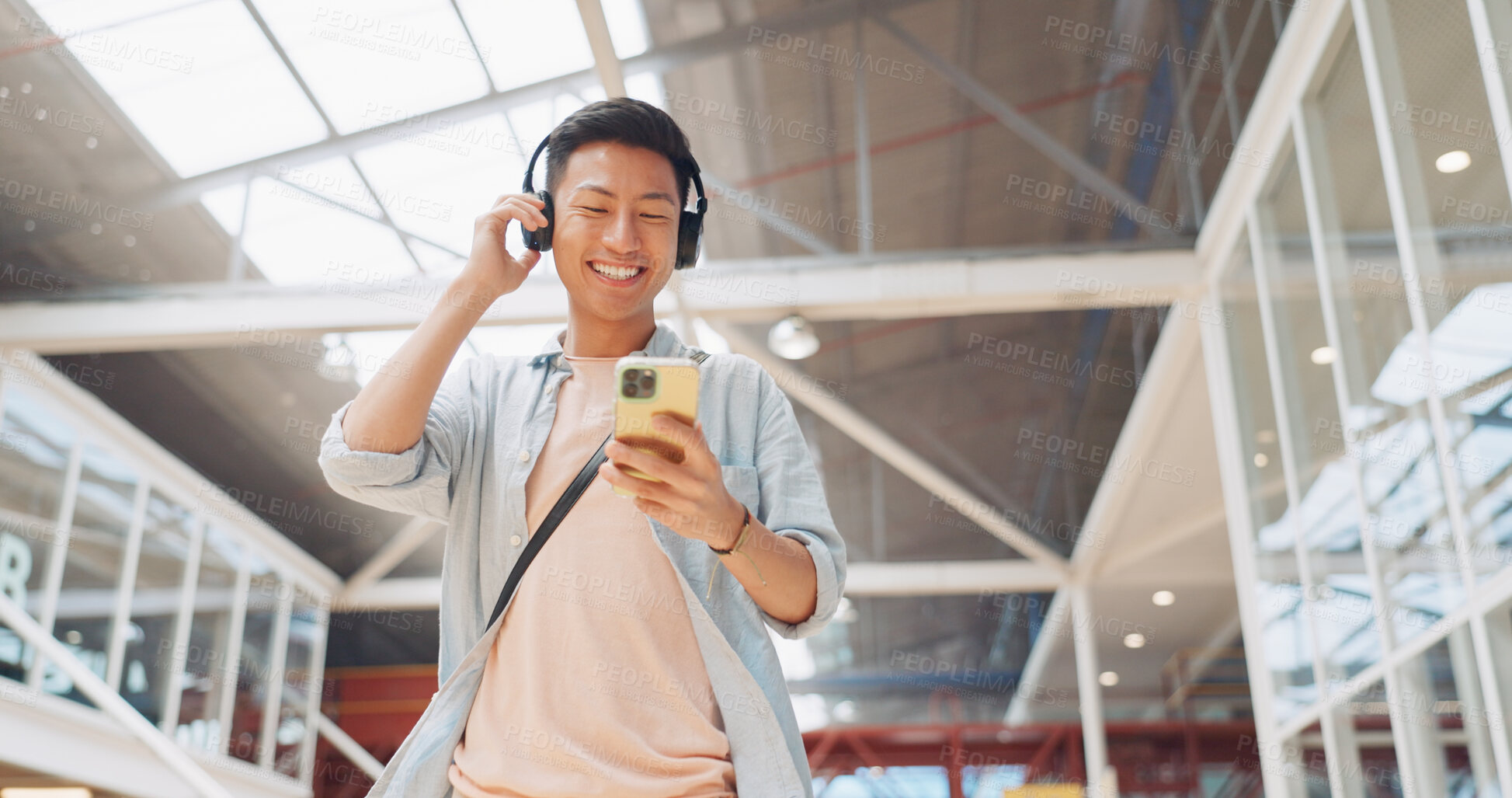 Buy stock photo Walking, phone or Asian man in office with headphones on social media, internet or network in a building. Podcast, travel or happy intern on mobile app to chat or scroll for radio music playlist