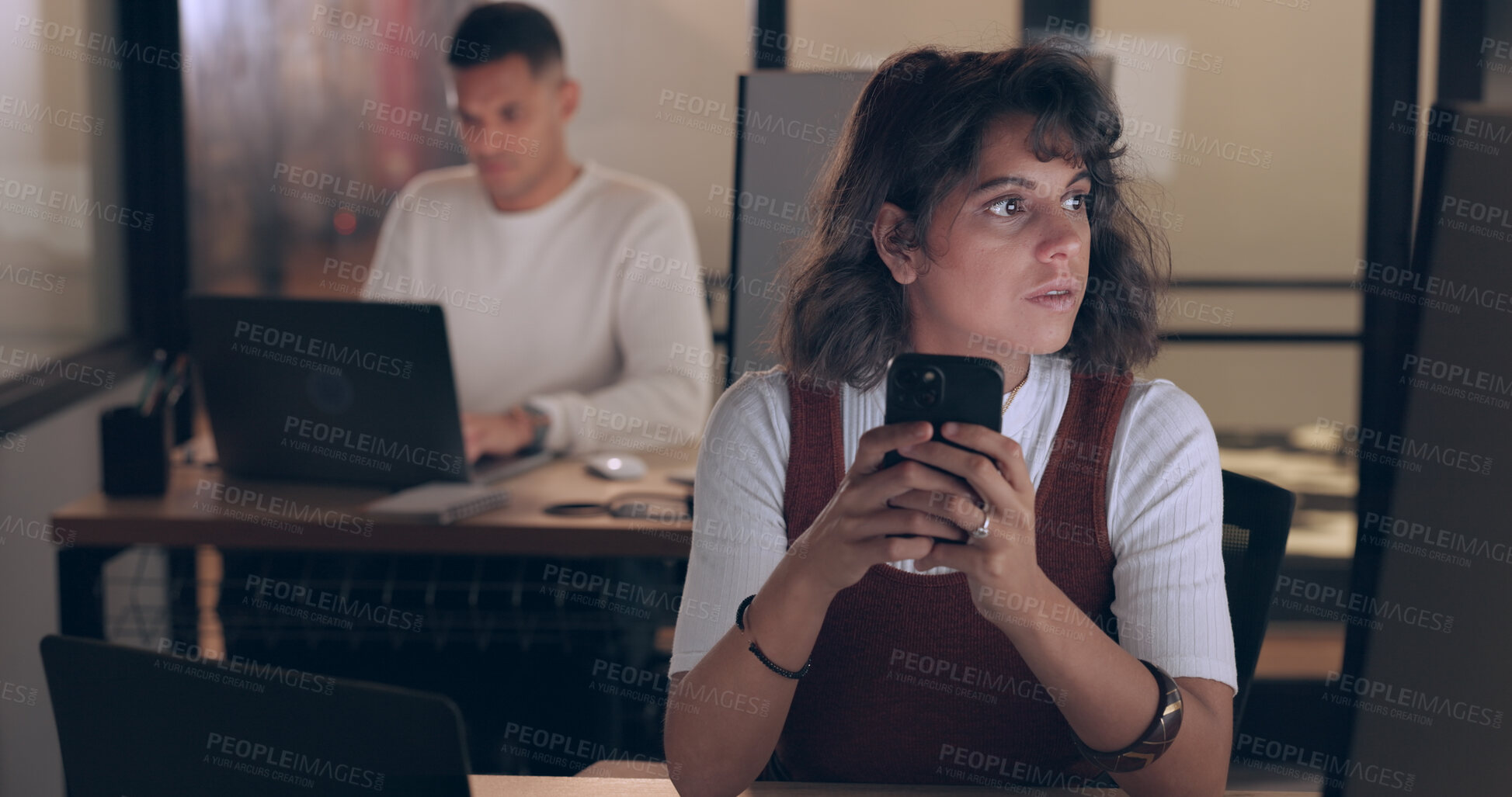 Buy stock photo Phone, night and business woman in office, reading email and information on computer for deadline. Mobile, creative and serious professional designer on internet, typing and communication in startup