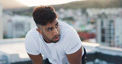 Fitness, city and tired man on a rooftop after running training, cardio workout and exercise outdoors. Runner, sports and healthy athlete exhausted with fatigue breathing or resting to recover energy