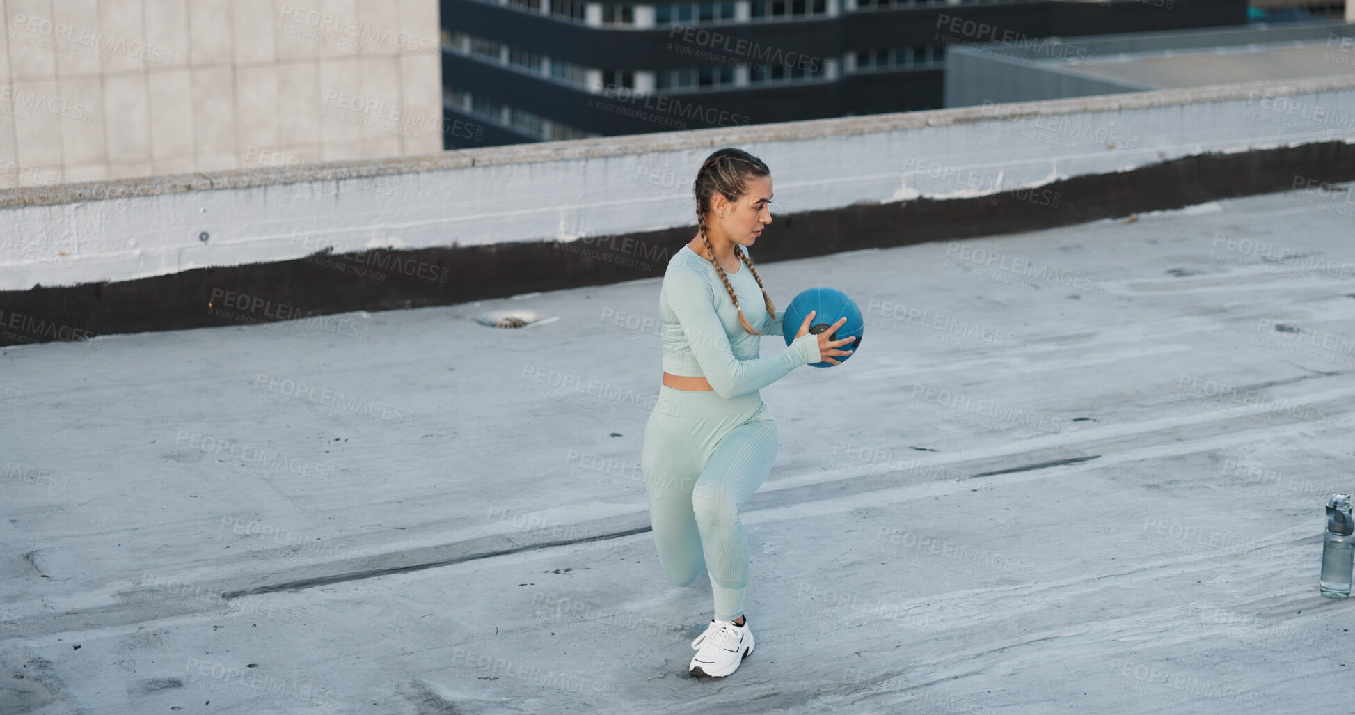 Buy stock photo Sports, medicine ball and woman athlete in the city for a health, wellness and cardio workout or exercise. Fitness, energy and young female person training on building rooftop in urban town.