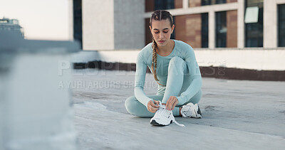 Fitness, workout and woman tie shoe before exercise outdoor on a rooftop in the city or New york. Female athlete prepare to start wellness training, sneakers or health cardio training in the morning