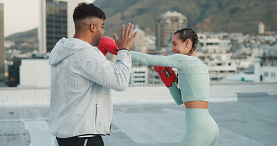 Fitness, personal trainer and woman boxing on a rooftop of a city building training in a cardio workout exercise. Smile, couple and happy fighting sports coach teaching a female boxer safety outdoors