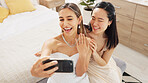 Bride, bridesmaid and selfie with phone, wedding and ring with a smile to post on social media. Happy woman and asian friend excited for marriage celebration with fashion white dress in a bedroom