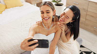 Bride, bridesmaid and selfie with phone, wedding and ring with a smile to post on social media. Happy woman and asian friend excited for marriage celebration with fashion white dress in a bedroom