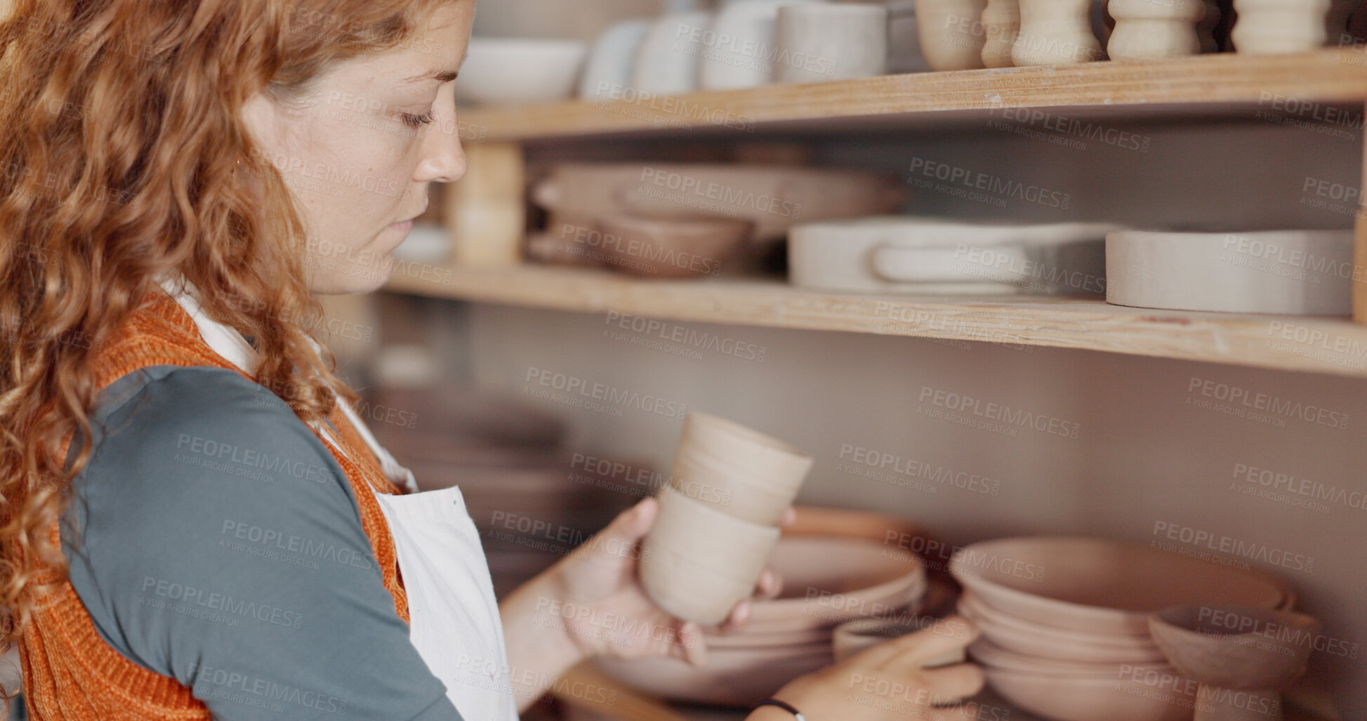 Buy stock photo Pottery, creativity and woman artist in workshop by a shelf for clay products in small business. Creative, mud design and young female sculptor checking or manufacturing ceramic art goods in a studio