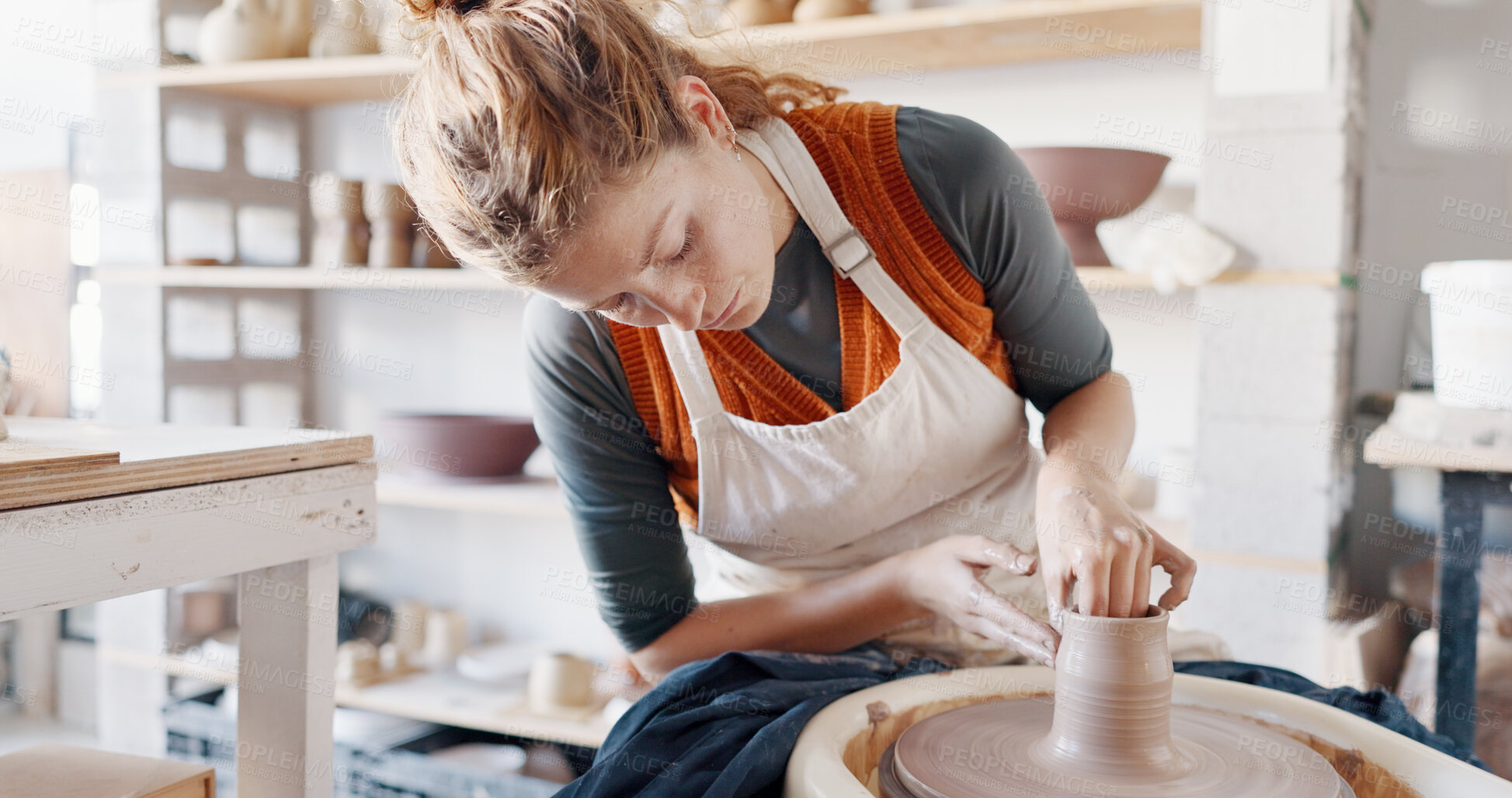 Buy stock photo Pottery, creative and woman artist by wheel for manufacturing clay products for small business. Art, mud design and young female sculptor working on ceramic handicraft goods fir production in studio.
