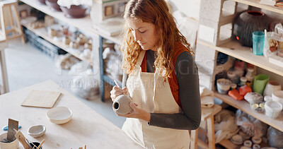Pottery, art and design woman artist in a home studio working on creative work. Ceramic arts designer or student at a learning workshop or house preparing a clay stencil pattern on a vase project