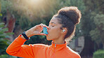 Young black woman athlete using asthma pump after his daily workout routine outside. Dedicated black women taking care of her health and wellness. Endorsing a healthy lifestyle by exercising and taking his medication outside in a forest