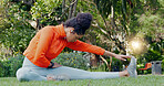 Black woman stretching leg in the park for fitness, health and wellness before a run. Exercise, sports and female athlete warm up training outside or in nature for mobility, flexibility and strength.