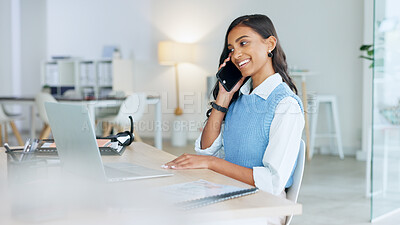 Young businesswoman using a laptop talking on her phone in an office. Trendy marketing professional on scheduled time, using the online app for networking, staying connected during office hours