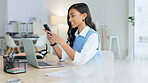 Young businesswoman using a laptop talking on her phone in an office. Trendy marketing professional on scheduled time, using the online app for networking, staying connected during office hours