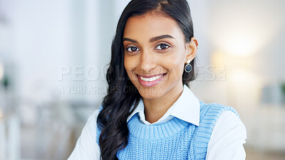 Portrait of a young designer smiling while working on a laptop in a modern office. Confident and happy indian business woman feeling ambitious and motivated for success in a creative startup agency