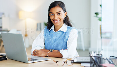 Portrait of a young business woman working online on a laptop alone in an office at work. Happy female corporate professional typing and sending emails. One expert manager browsing the internet