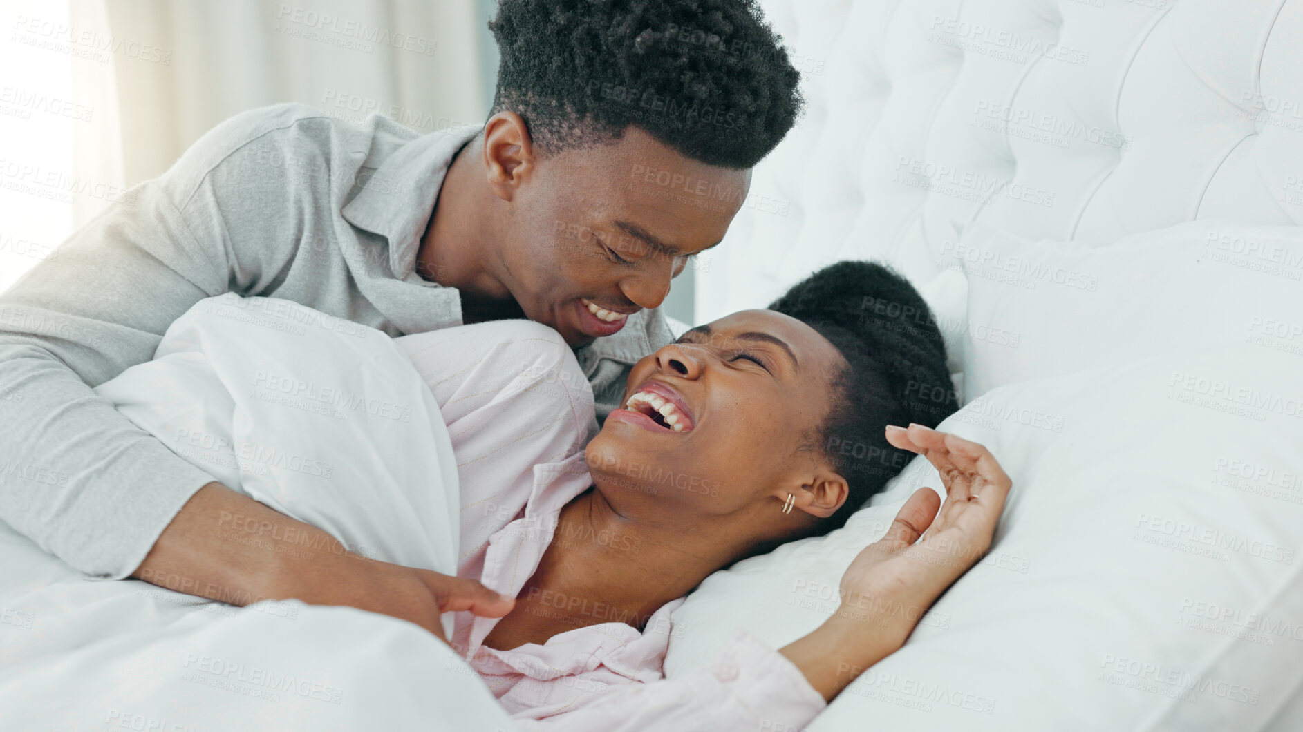 Buy stock photo Smile, love and black couple cuddle in bed, bonding and wake up in home. Bedroom, embrace and happy man and woman in healthy relationship, romantic connection and funny laugh together in the morning