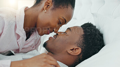 Love, smile and happy intimate couple in bed in the morning while talk and bonding together. Black man and woman relax, conversation and communication trust, support and quality time in home bedroom