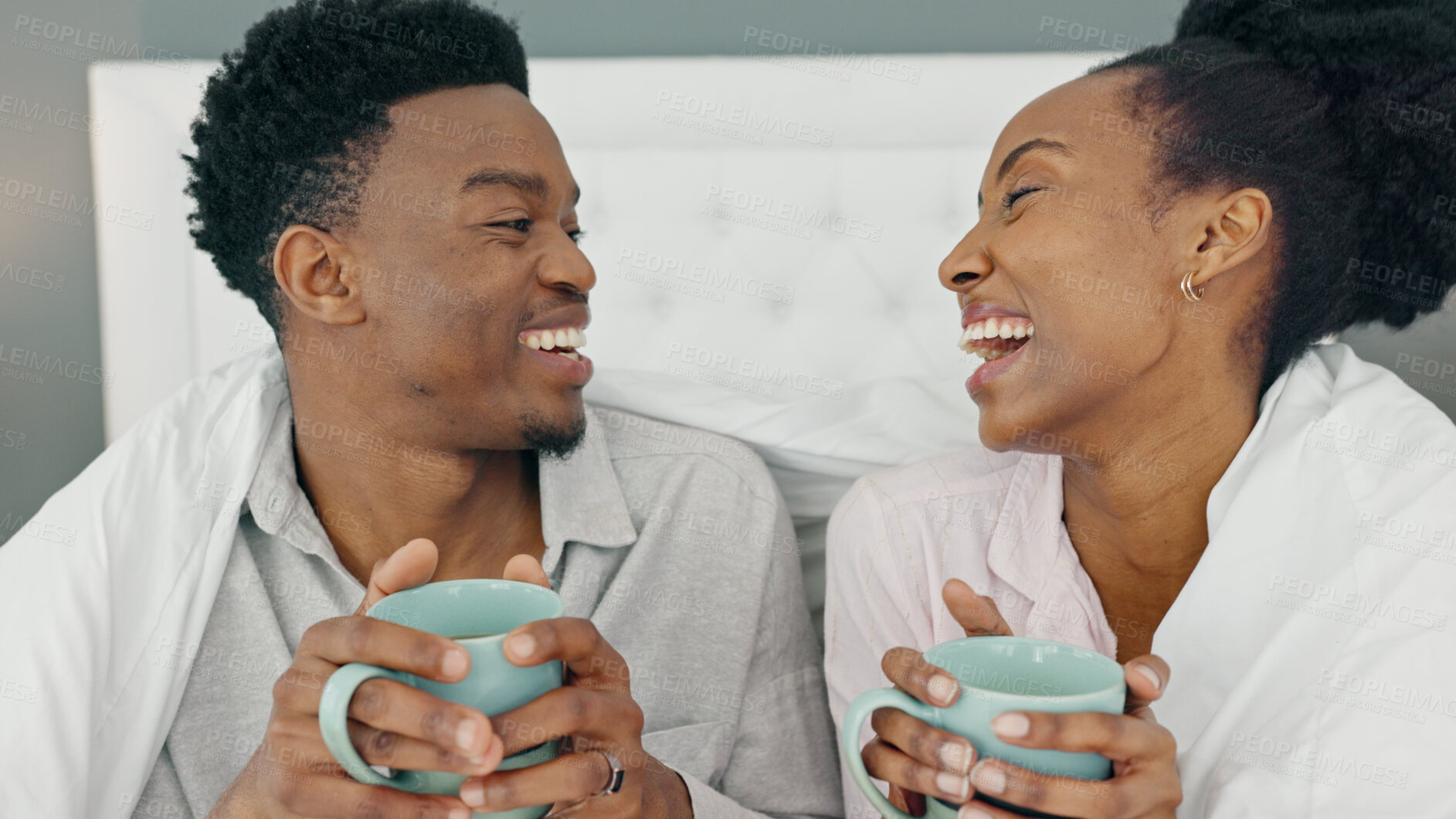 Buy stock photo Coffee, bed and couple relax and laughing in their home bedroom together. Drink, tea and morning with a funny black man and woman with care, comfort and support in healthy and happy marriage