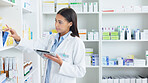 A young female pharmacist stocktaking in a dispensary using a tablet. Doctor preparing prescriptions and medication at clinic or pharmacy. Healthcare professional sorting medicine with digital device