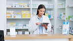 Portrait of a cheerful and friendly pharmacist using a digital tablet to check inventory or online orders in a chemist. Young latino woman using pharma app to do research on medication in a pharmacy