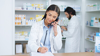 Pharmacist woman answering the telephone and giving advice to customer on flu shot treatment options in pharmacy. Chemist assisting remote client by checking medicine stock on their computer database