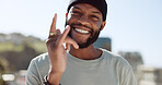 Hand, happy and sign with a black man showing a gesture while standing outdoor in the city with a smile on his face. Portrait, freedom and carefree with a young male gesturing or signing in a town