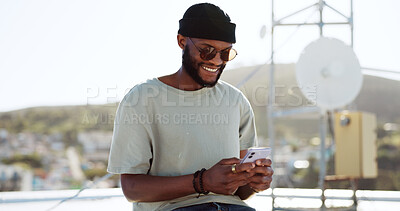 Phone, texting and happy black man on rooftop of city building using smartphone for social media, chatting and communication. Fashion, meme and young trendy guy typing message, text or post in town