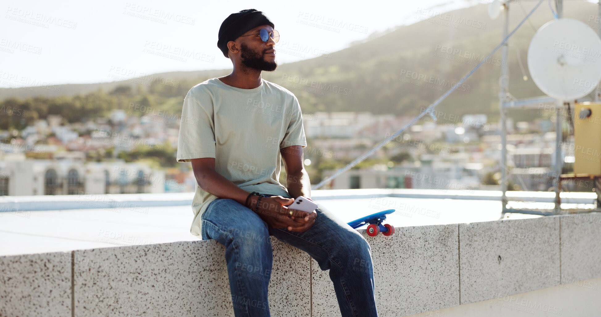 Buy stock photo Black man, relax and thinking on wall with skateboard, building rooftop in city and calm with solution. African person, skater and guy with ideas, serene and happy with sunshine, wonder and adventure