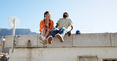 Love, friendship and a couple sitting on rooftop of city building in summer time. Diversity, friends and romance, gen z urban dating for happy woman and black man with smile and skateboard on date.