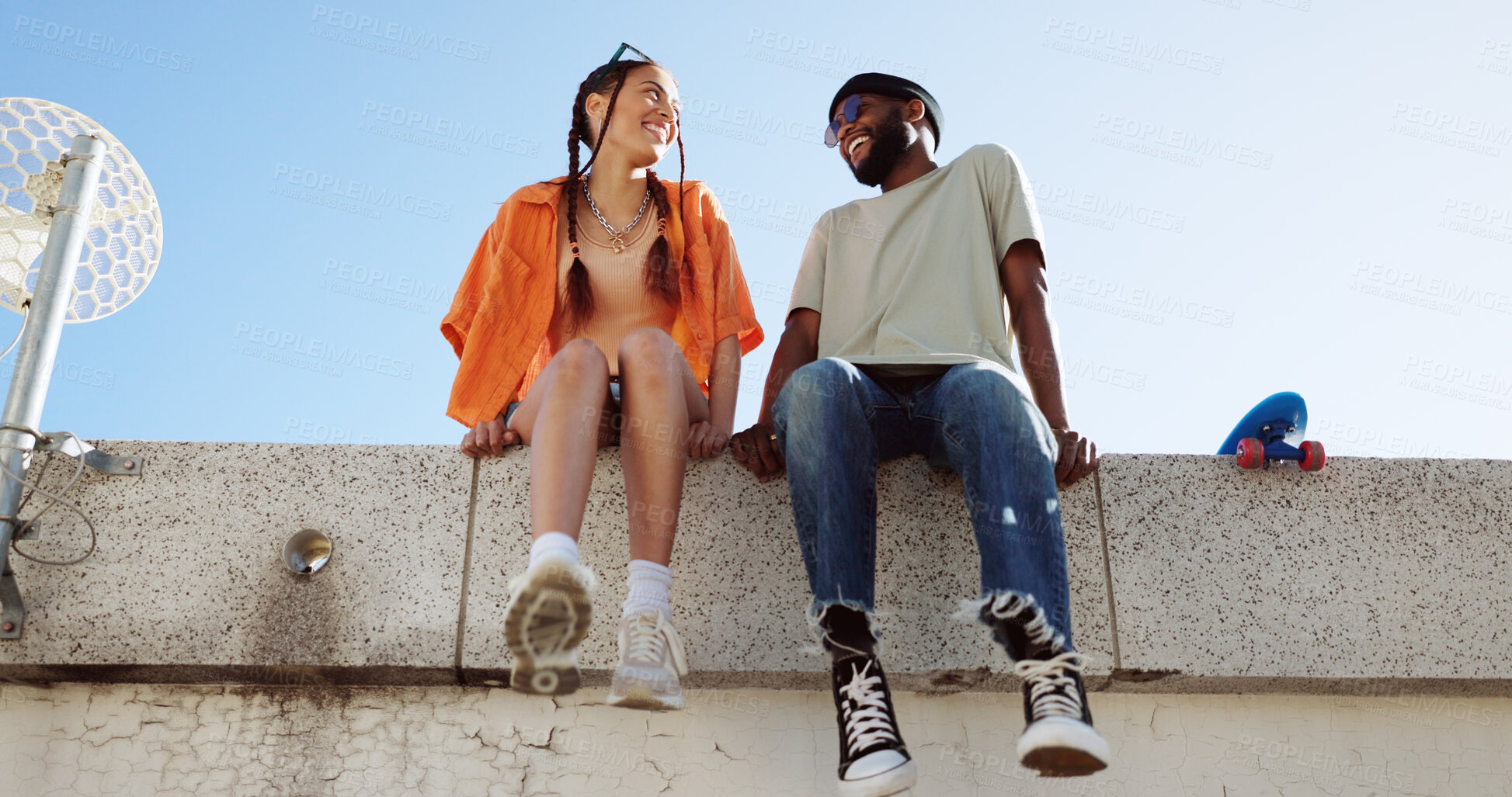 Buy stock photo Couple of friends, happy and sitting on rooftop with funny conversation, love and laughing. African man and trendy gen z woman together for travel, urban date and freedom or relax in Los Angeles