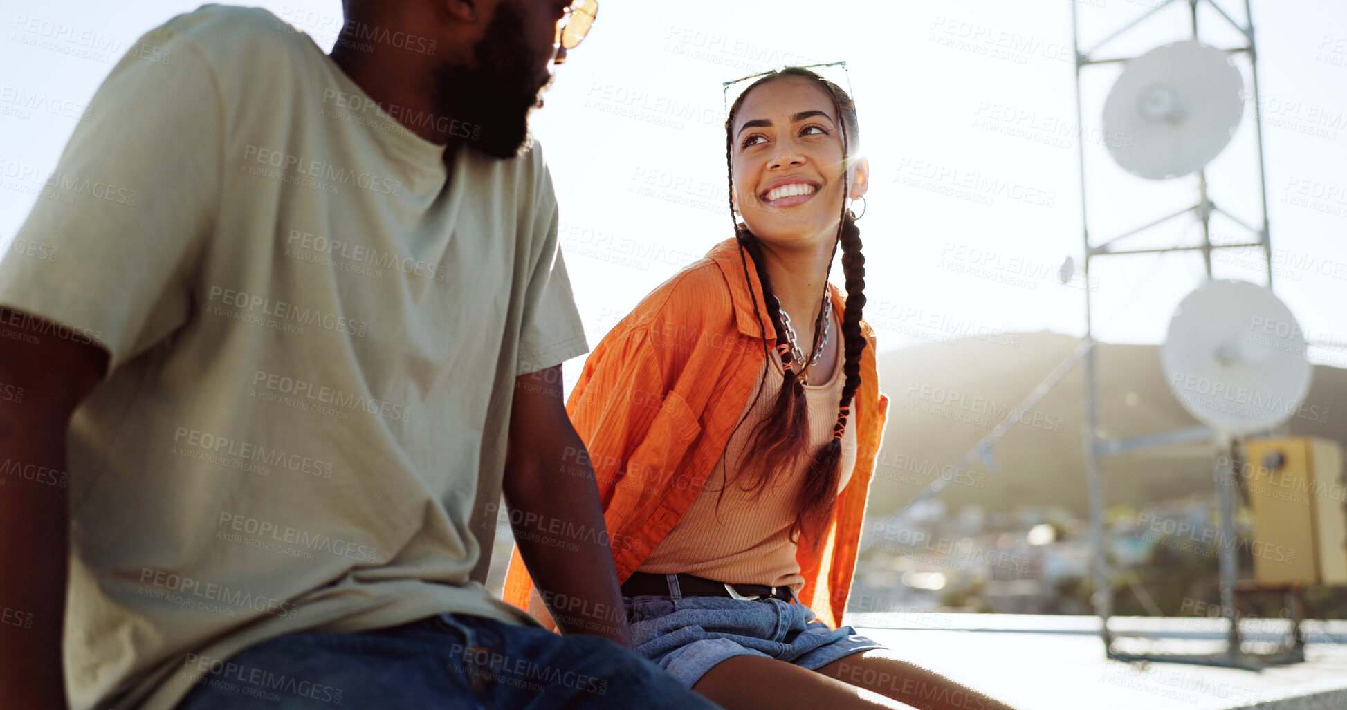 Buy stock photo Happy woman, man and rooftop date on city building, talking and youth bonding with freedom. Diversity, gen z couple of friends sitting on roof with smile, love and relax on urban social together.