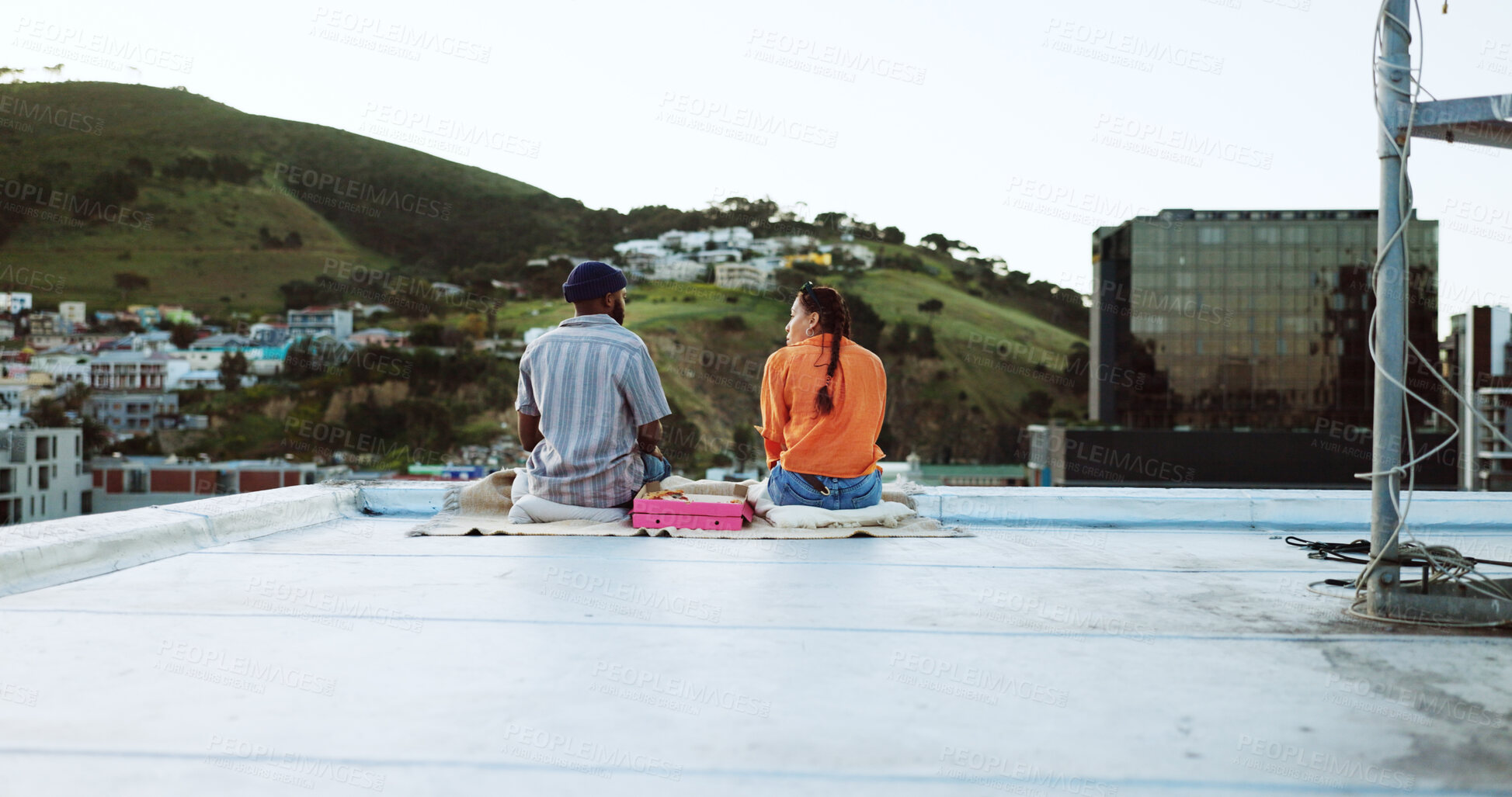 Buy stock photo Couple, talking and sitting outdoor on rooftop for picnic, love and happiness. Behind a man and woman together for city travel, urban date and freedom or relax with conversation in Cape Town