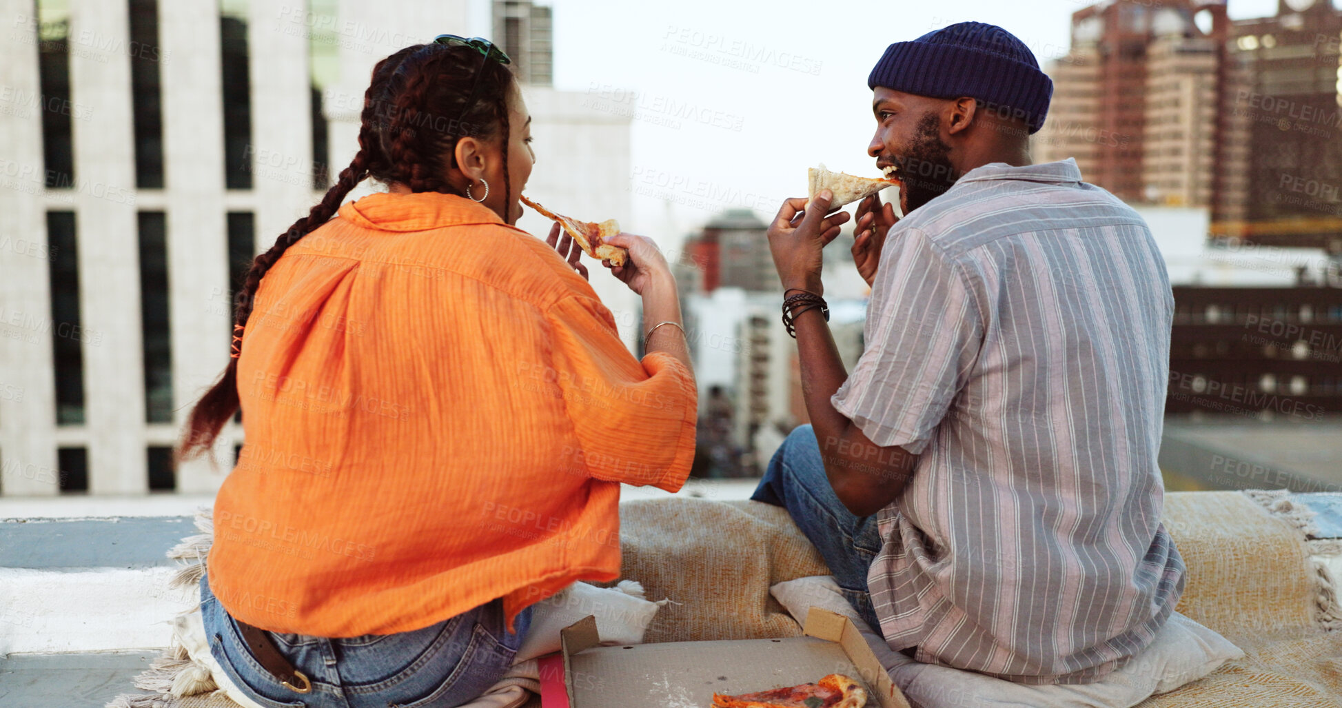 Buy stock photo Couple, food and pizza outdoor in city for rooftop picnic, love or happiness. Behind man and woman eating together for travel, urban date and freedom or relax with adventure and cityscape in New York