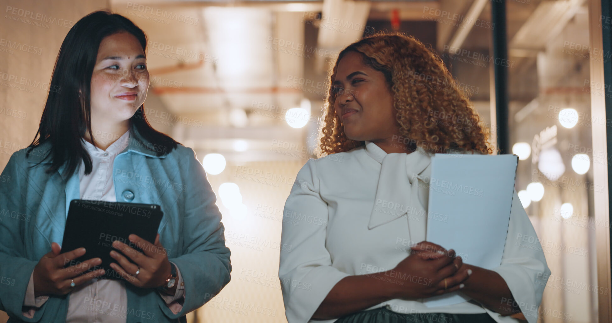 Buy stock photo Tablet, documents and business women walking in the office together while planning or talking at night. Technology, collaboration and diversity with an employee team in discussion at the workplace