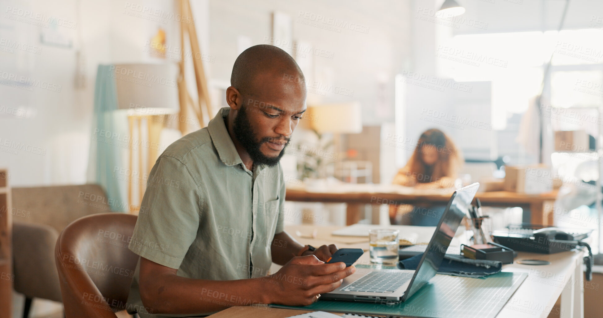 Buy stock photo Laptop, phone and social media with a black man designer in an office for work on a creative project. Technology, communication or networking with a young employee in a workplace for design marketing