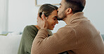 Love, support and happy with a couple in their home together, sharing an intimate moment with a kiss. Smile, talking and romance with a young man and woman kissing on a sofa in the living room