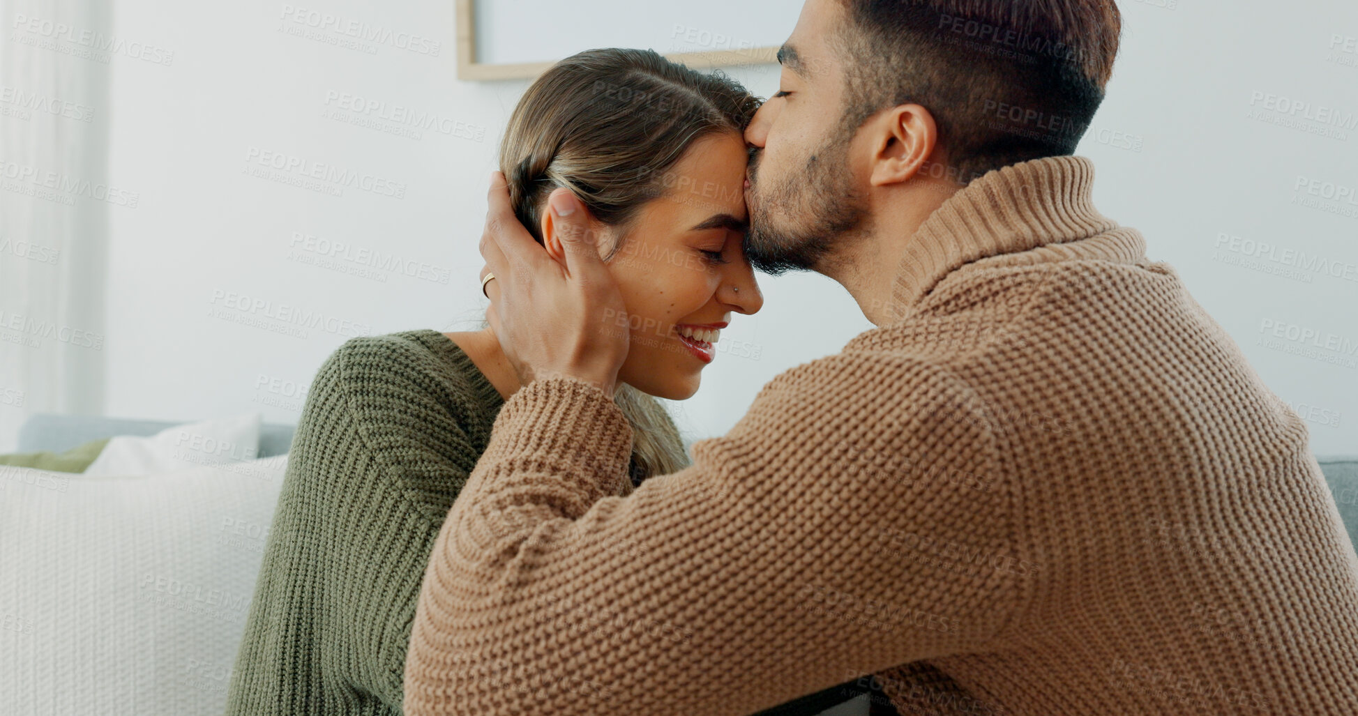 Buy stock photo Forehead, kiss and happy couple in home with love, support and  moment together in marriage, romance or partnership. Woman, smile and man kissing face on sofa in apartment, living room or house