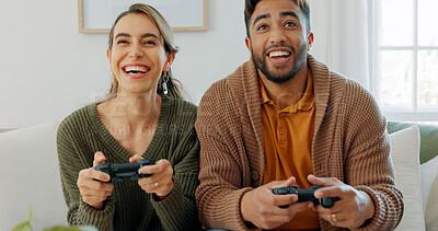Fun, playing and love with a gamer couple laughing, joking or bonding while gaming on a sofa in the living room of their home together. Game, funny and laugh with a man and woman enjoying video games