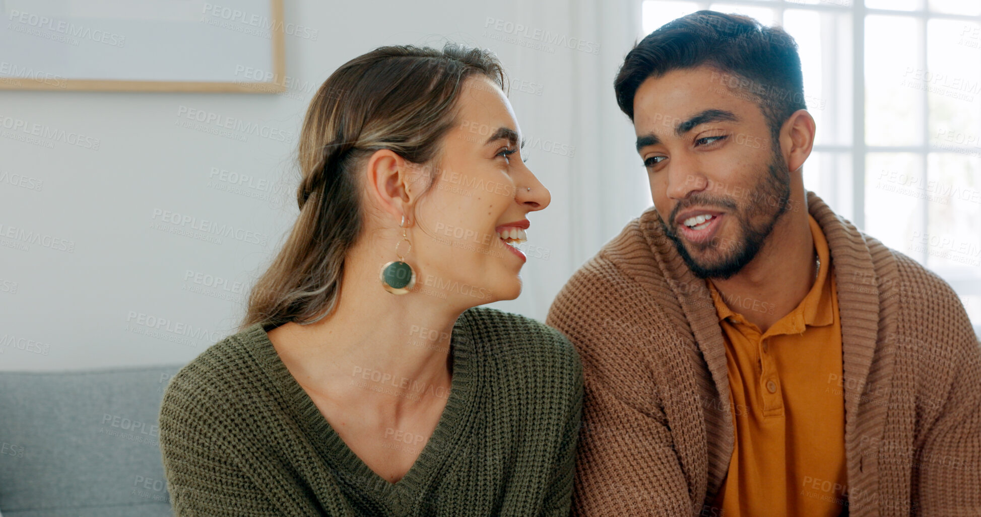 Buy stock photo Love, smile and an interracial couple in their home on a sofa in the living room together to relax. Diversity, happy or romance with a young man and woman in their house for relationship bonding