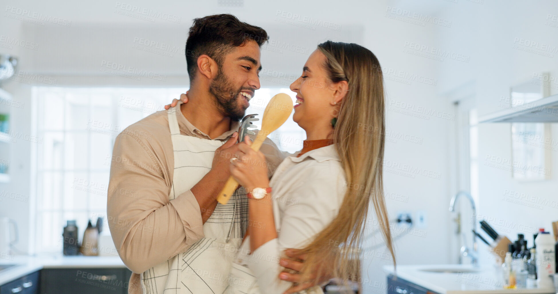 Buy stock photo Couple, cooking and singing in home kitchen, hug and playful with romance, love and concert with spoon mic. Man, woman and funny with karaoke, comic performance and laughing with music for nutrition