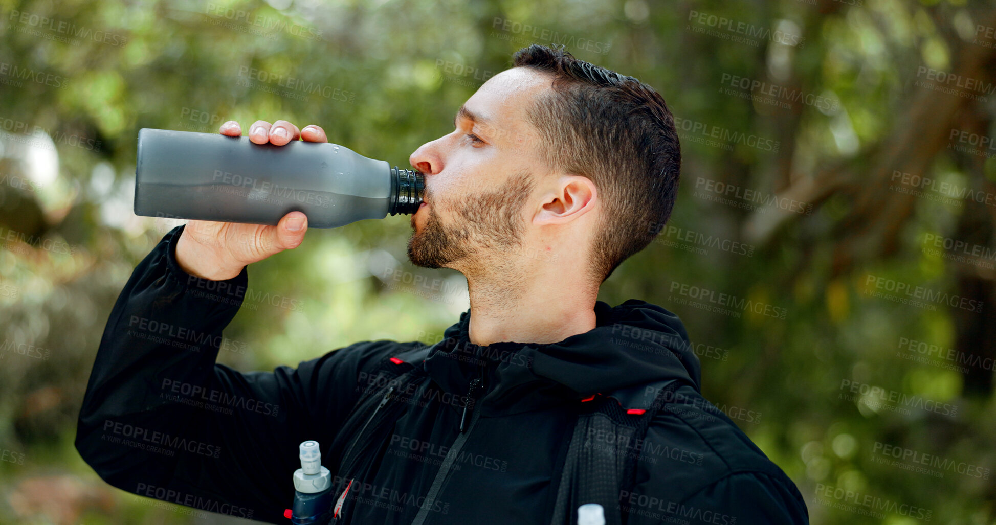 Buy stock photo Hiking, nature and man drinking water in bottle while on outdoor adventure trail hike in forest. Travel, freedom and healthy young guy enjoying refreshing drink for hydration while trekking in woods.