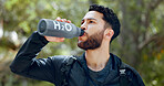 Man drinking water hiking in a forest, nature or woods outdoors in jungle adventure with freedom in Costa Rica. Healthy, fitness and thirsty hiker trekking or walking on a journey refreshing on break