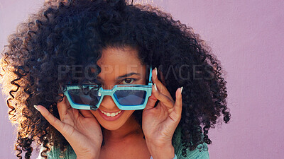 Black woman with sunglasses, smile, laugh and play with hair against pink backdrop in sunshine. Model girl with curly afro hair, happy with blue fashion glasses against pink wall or background