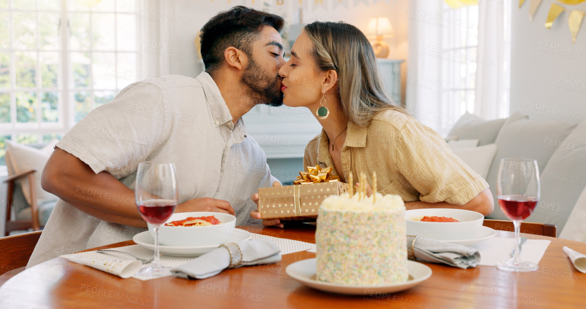 Buy stock photo Cake, gift and kiss or birthday, with couple celebration and present together with love at home. Candles, wine and happy people with dinner date and food in a house party with support and alcohol