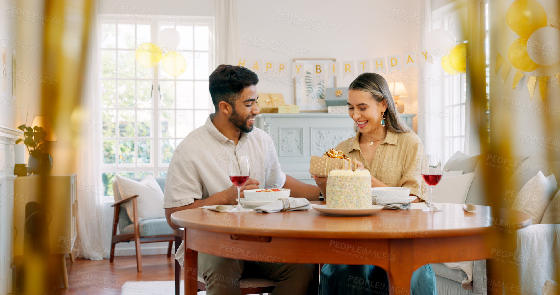 Buy stock photo Birthday cake, celebration and present with couple, love and date together in home living room with drink. Happy, smile and people with conversation and gift with dessert and alcohol and talking