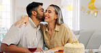 Interracial couple, gift and celebrate birthday being happy, kiss and smile in home at table with cake. Love, man and woman being content, romantic and present being cheerful celebration together.