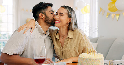 Interracial couple, gift and celebrate birthday being happy, kiss and smile in home at table with cake. Love, man and woman being content, romantic and present being cheerful celebration together.