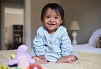Happy baby with down syndrome, portrait on bed with smile of Mexican kid with special needs relaxed in home. Happy toddler girl in Mexico with disability and cheerful joy sitting in bedroom