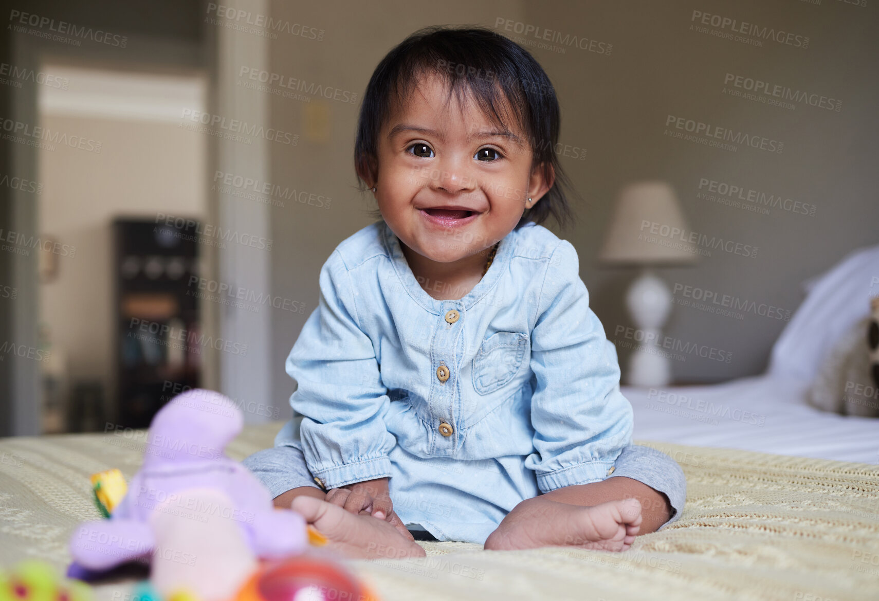 Buy stock photo Happy baby with down syndrome, portrait on bed with smile of Mexican kid with special needs relaxed in home. Happy toddler girl in Mexico with disability and cheerful joy sitting in bedroom