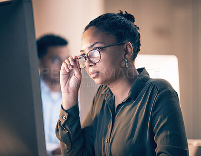 Buy stock photo Serious black woman, computer and reading email, code or corporate information at night by the office. African American female employee focusing with glasses on PC working late at the workplace