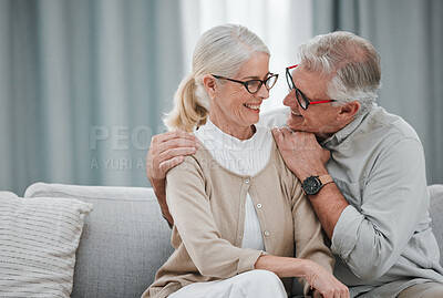 Buy stock photo Love, hug and mockup with a senior couple sitting on a sofa in the living room of their home together. Romance, affection or mock up with a mature man and woman hugging or bonding in their house